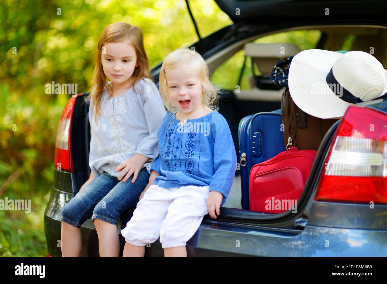 Zwei entzückenden kleinen Schwestern in einem Auto sitzen nur vor dem Verlassen für ein Auto Urlaub mit ihren Eltern Stockfoto
