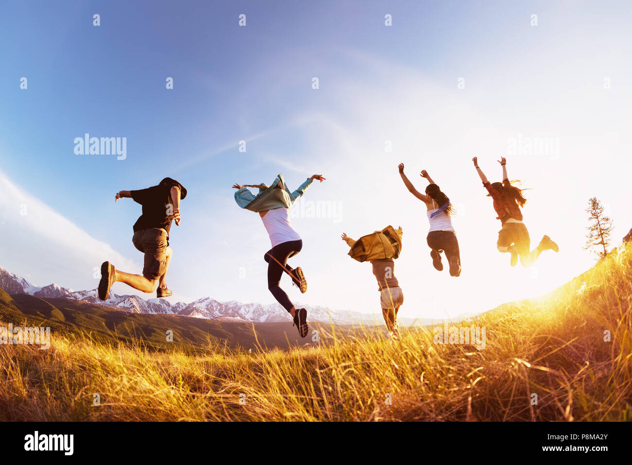 Gruppe von fünf glückliche Freunde läuft und springt gegen die Berge bei Sonnenuntergang. Reisen oder Expeditionen Konzept Stockfoto