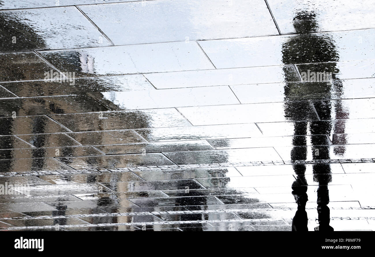 Unscharfe Reflexion Schatten Silhouetten der Paar auf dunklen regnerischen city street Stockfoto