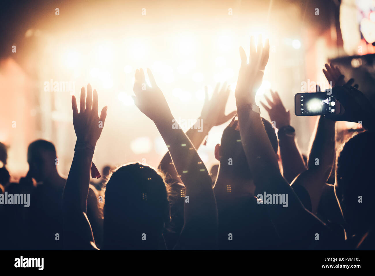 Jubelnde Menge mit Händen in der Luft bei Music Festival Stockfoto