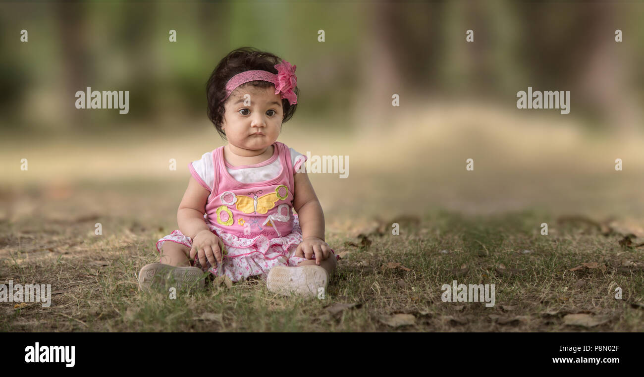 Traurig Baby Mädchen sitzen auf grünem Gras, selektive konzentrieren. geringe Tiefenschärfe. Stockfoto