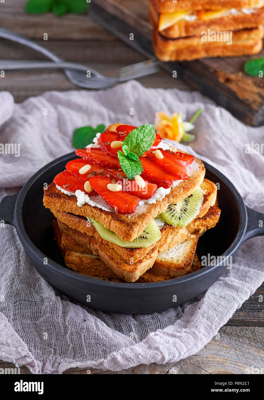 Stapel der French Toast mit frischen Erdbeeren und Kiwis in einer Runde, schwarze Pfanne auf dem Tisch Stockfoto