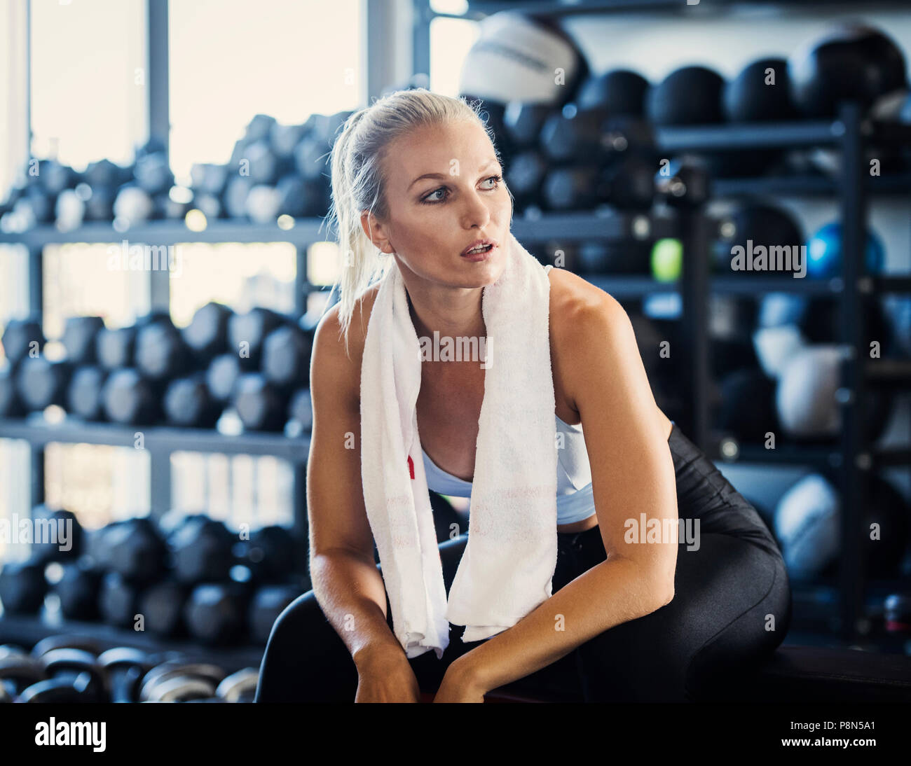 Junge Frau mit Handtuch im Fitnessstudio Stockfoto