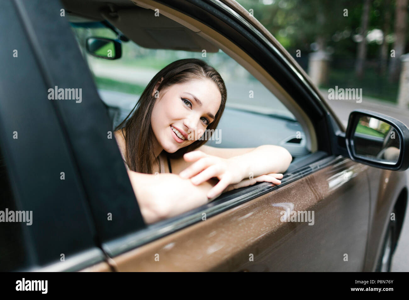 Lächelnde junge Frau sitzt im Auto Stockfoto