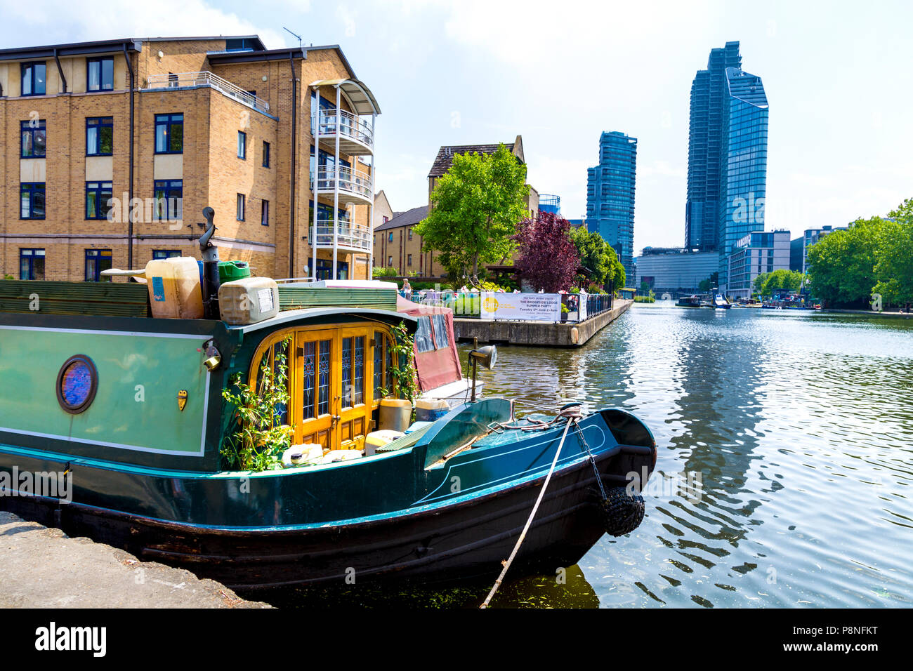 Ein gemütliches Hausboot Liegeplatz auf der Regents Canal mit luxuriösen Wohn- Hochhäuser im Hintergrund, London, UK Stockfoto