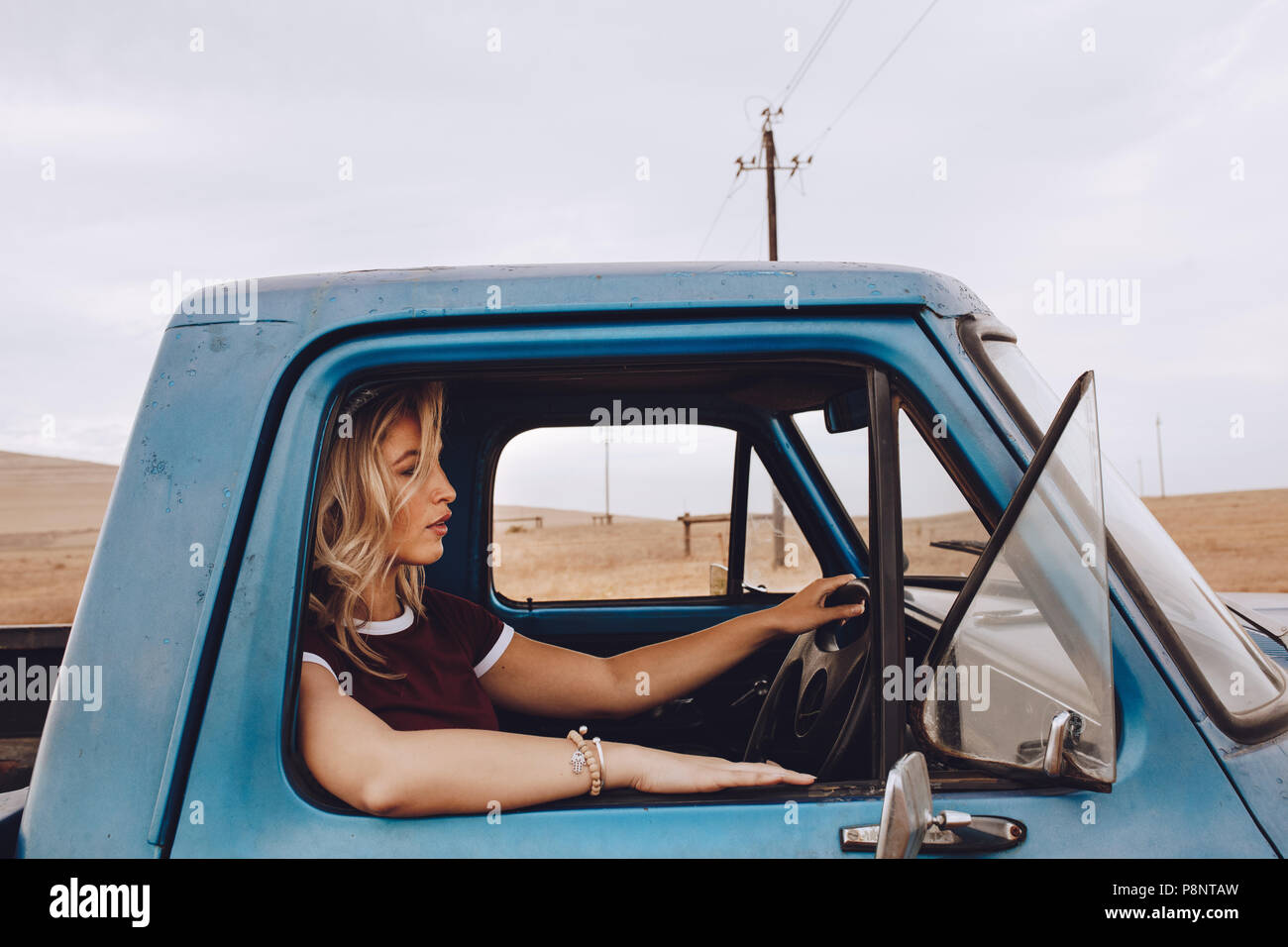 Seitenansicht der jungen Frau, die ein Lkw auf der Landstraße. Weibliche auf einer Fahrt mit dem Auto. Stockfoto