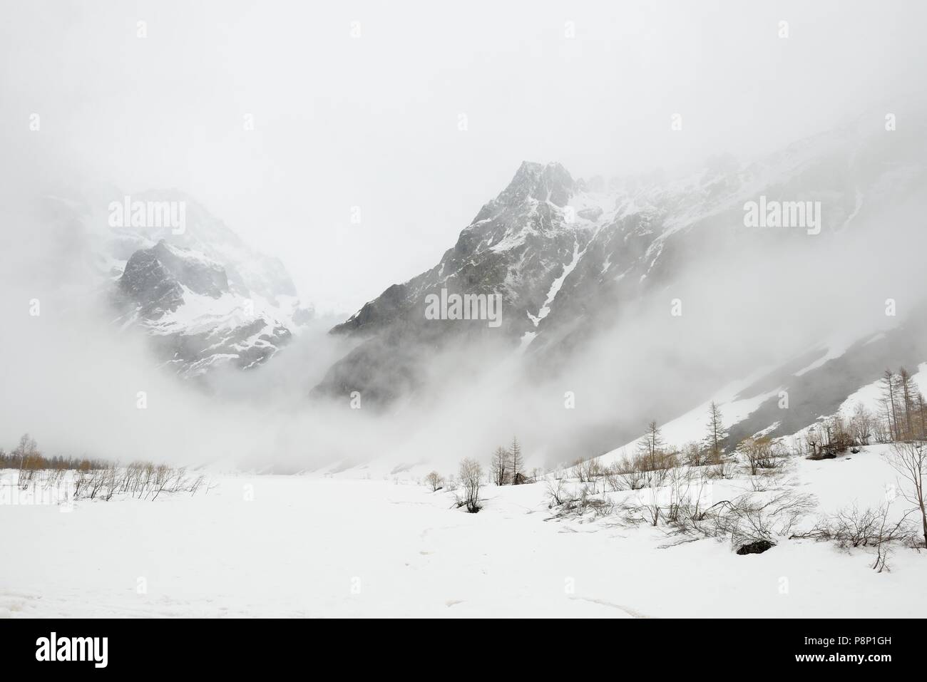 Dramatische Atmosphäre im Frühling in den französischen Alpen mit dem Schnee schmelzen und tief hängenden Wolken Stockfoto