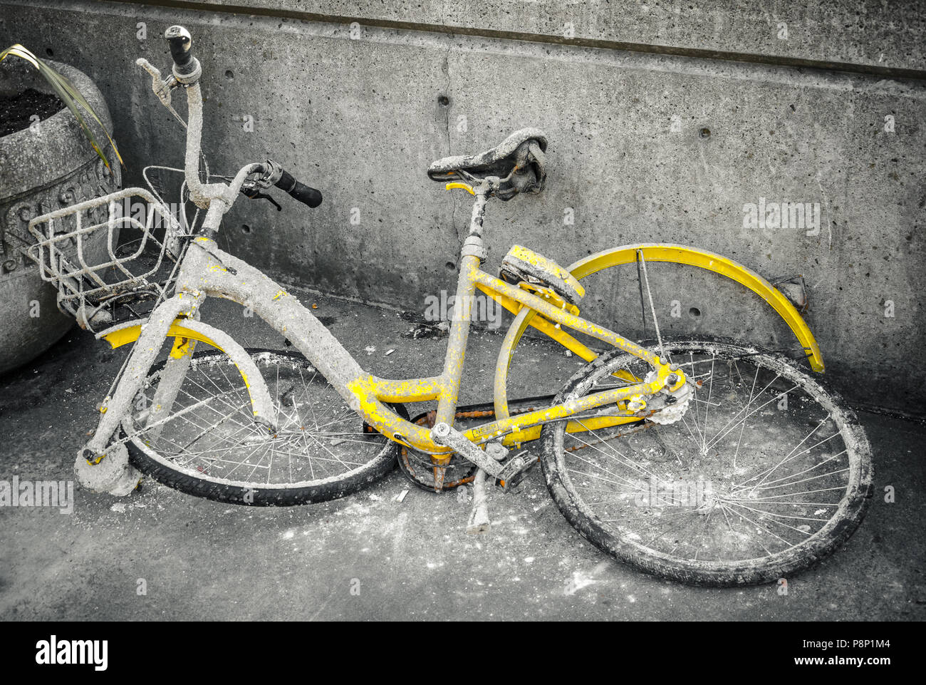 Eine rostige, verfallenen gelb Fahrrad mit verrückten Räder liegt an der Ecke einer Straße in der Stadt. Stockfoto