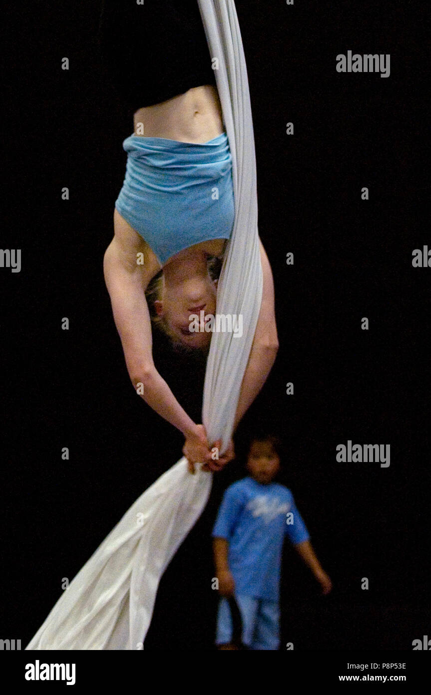 Ein Junge sieht sich als weibliche Acrobat sich auf den Kopf setzt sich mit dem Einsatz von Antenne Seiden. Stockfoto