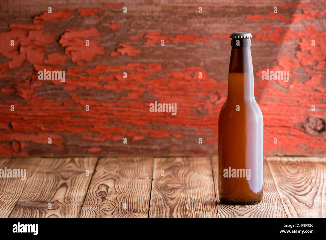 Single unbeschriftete bedeckte voll Bier Flasche auf eine rustikale Holz Hintergrund mit Peeling verwitterten roter Farbe und Raum kopieren Stockfoto