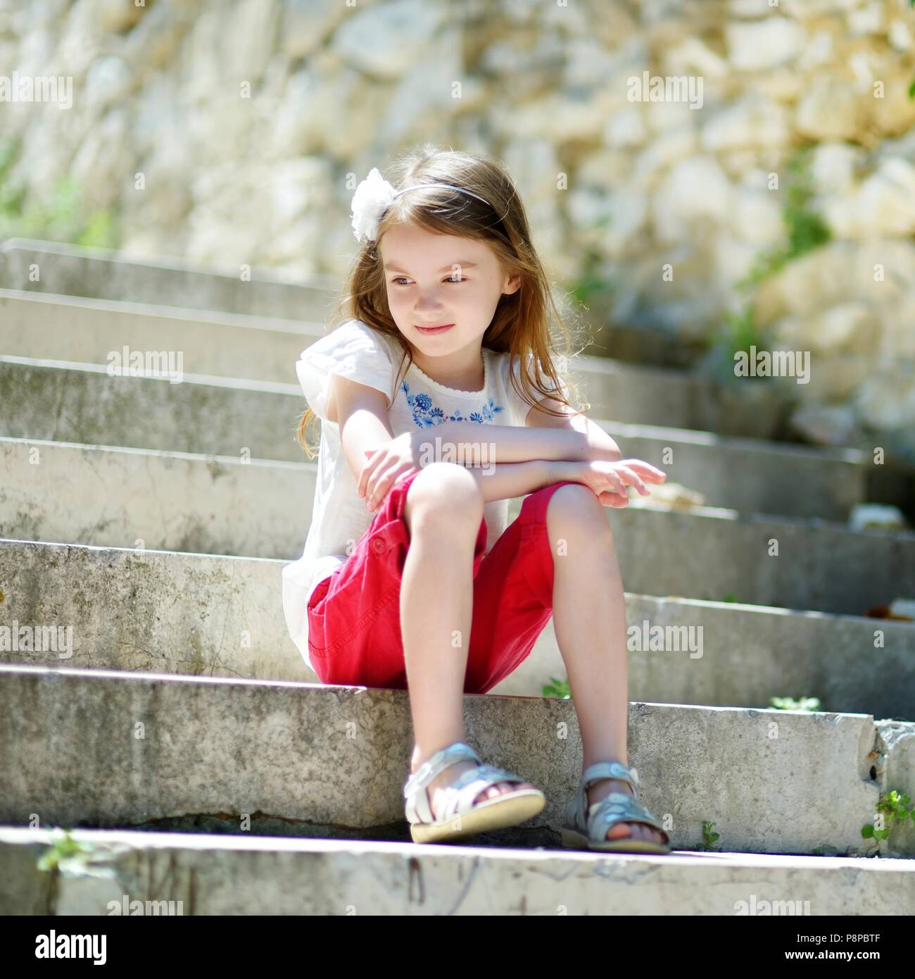Adorable kleine Mädchen sitzt auf der Treppe, an warmen und sonnigen Sommertag im typisch italienischen Stadt Stockfoto