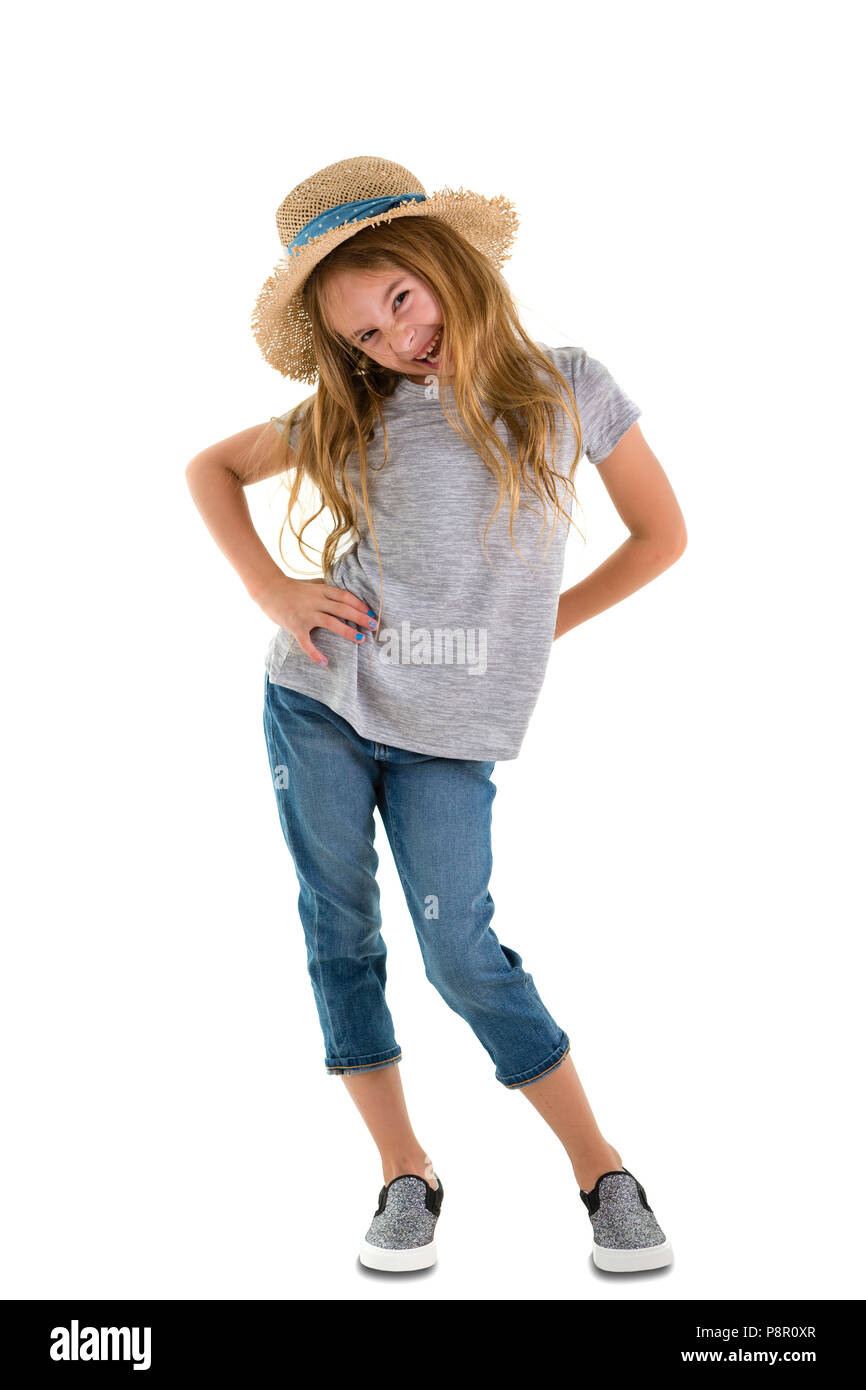 Spitzbübisch verspielt 6-jähriges kleines Mädchen mit langen Zerzausten blondes Haar und ein nettes Grinsen tragen trendy Jeans und einen Strohhut auf den Hi Stockfoto