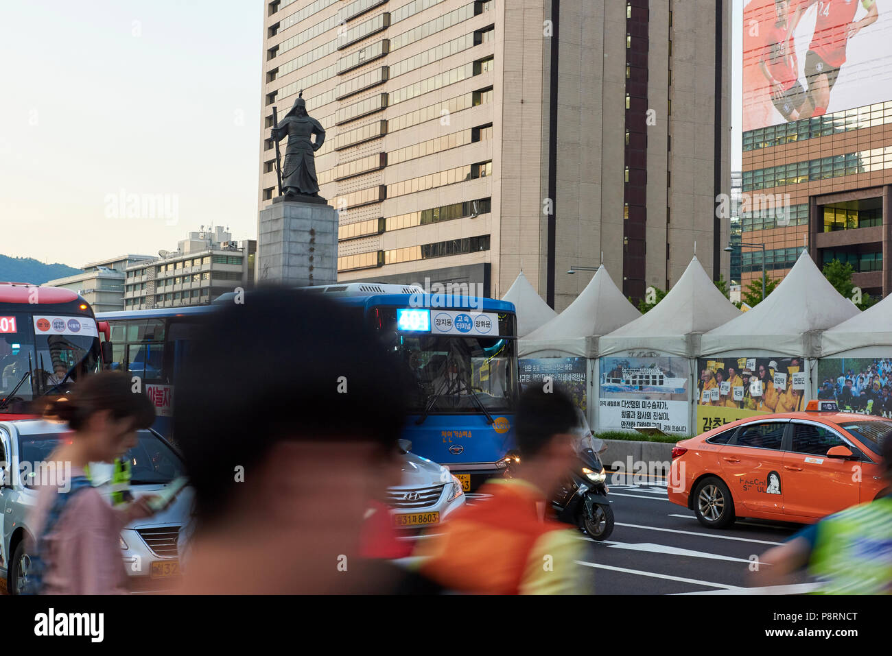 Statue von Admiral Yi Sun-Shin in Gwanghwamun, Seoul, Südkorea, mit Bewegung verwischt Fußgänger über die Straße in den Vordergrund. Stockfoto