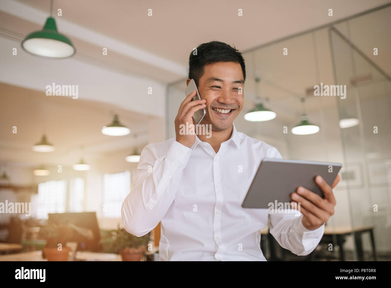 Asiatische Geschäftsmann mit einem Tablet und über sein Handy Stockfoto