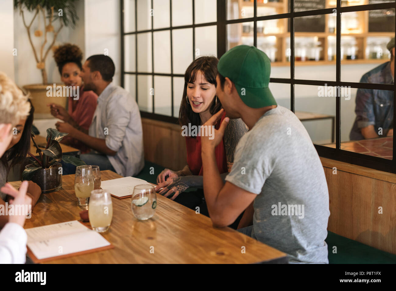 Lächelnd Freunde sitzen und sprechen zusammen an einem Bistrotisch Stockfoto