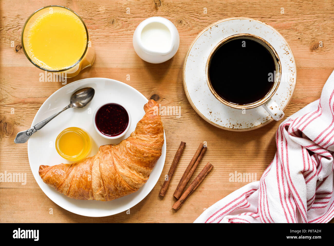 Frühstück mit Kaffee, Croissants, Marmelade, Orangensaft und Marmelade. Lecker Frühstück auf Holztisch, Ansicht von oben Stockfoto