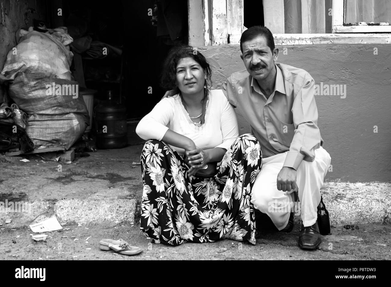 Schlechte mittleren Alter Zigeuner Paar - Türkisch Roma - sitzen auf dem Bürgersteig vor einem Haus in Elendsvierteln Kagithane Gultepe, Istanbul Türkei Stockfoto