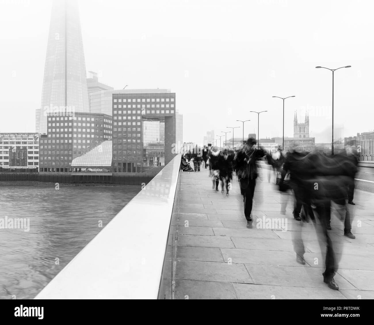 Montag morgen Pendler gehen auf die London Bridge über der Themse und gegenüber der Stadt und den Shard auf einem nebligen Tag arbeiten. Stockfoto