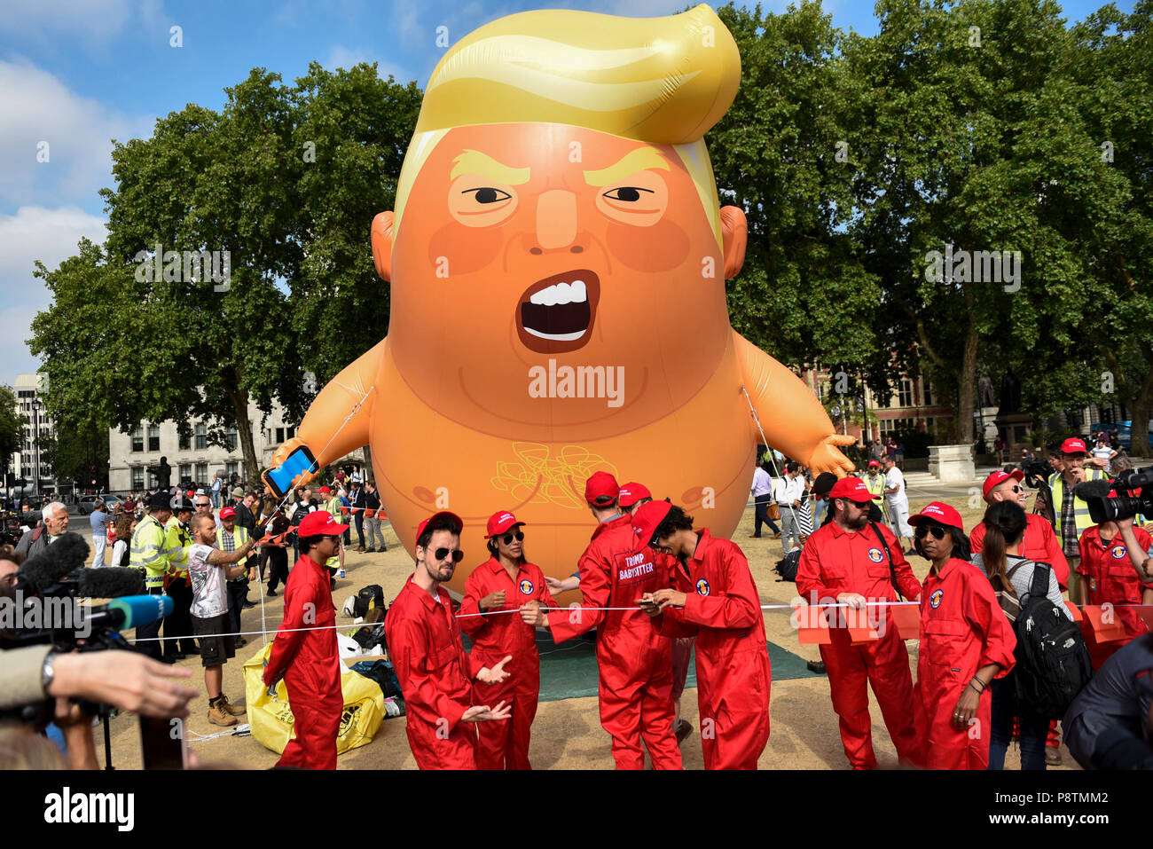 London, Großbritannien. 13. Juli 2018. Veranstalter pose mit einem riesigen "Trump Baby' Ballon gebildet werden bereit, über das Parlament in Westminster als Teil einer Protest gegen Präsident Donald Trump Besuch in Großbritannien fliegen. Veranstalter haben die 6 m hohen BLIMP entwickelt, Fliegen in einer Höhe von 30 m, das Donald Trump als Baby mit kleinen Händen, mit Handy und trug eine Windel. Massenproteste werden voraussichtlich auch im Zentrum von London, in Reaktion auf den Besuch des Präsidenten. Credit: Stephen Chung/Alamy leben Nachrichten Stockfoto