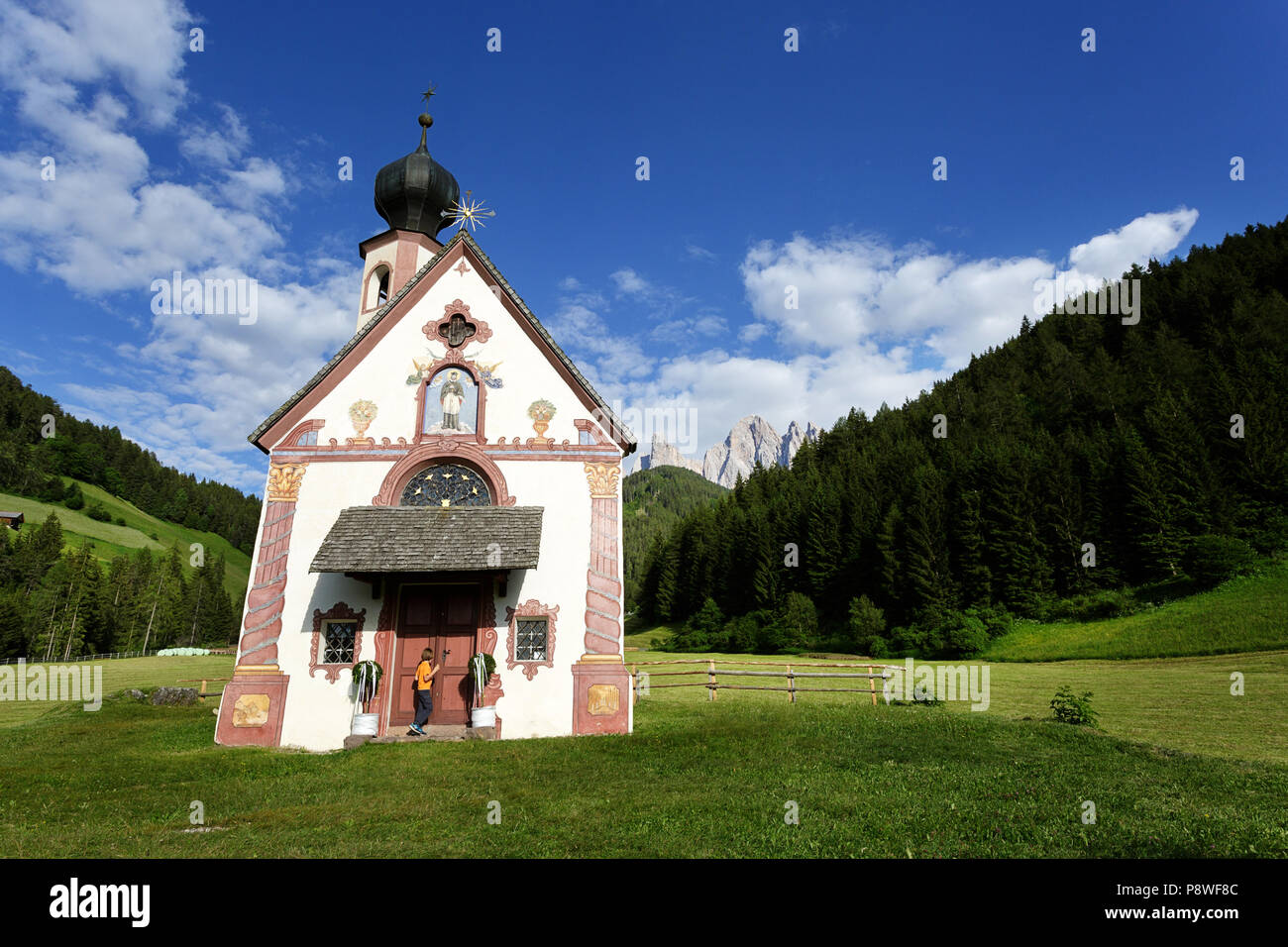 Junge Junge, der an der Tür der Kapelle in Santa Maddalena, Tirol, Dolomiten, Italien Stockfoto