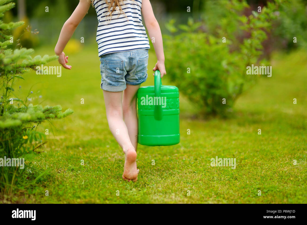Adorable kleine Vorschüler Mädchen Bewässerung Blumen und Pflanzen im Garten Stockfoto