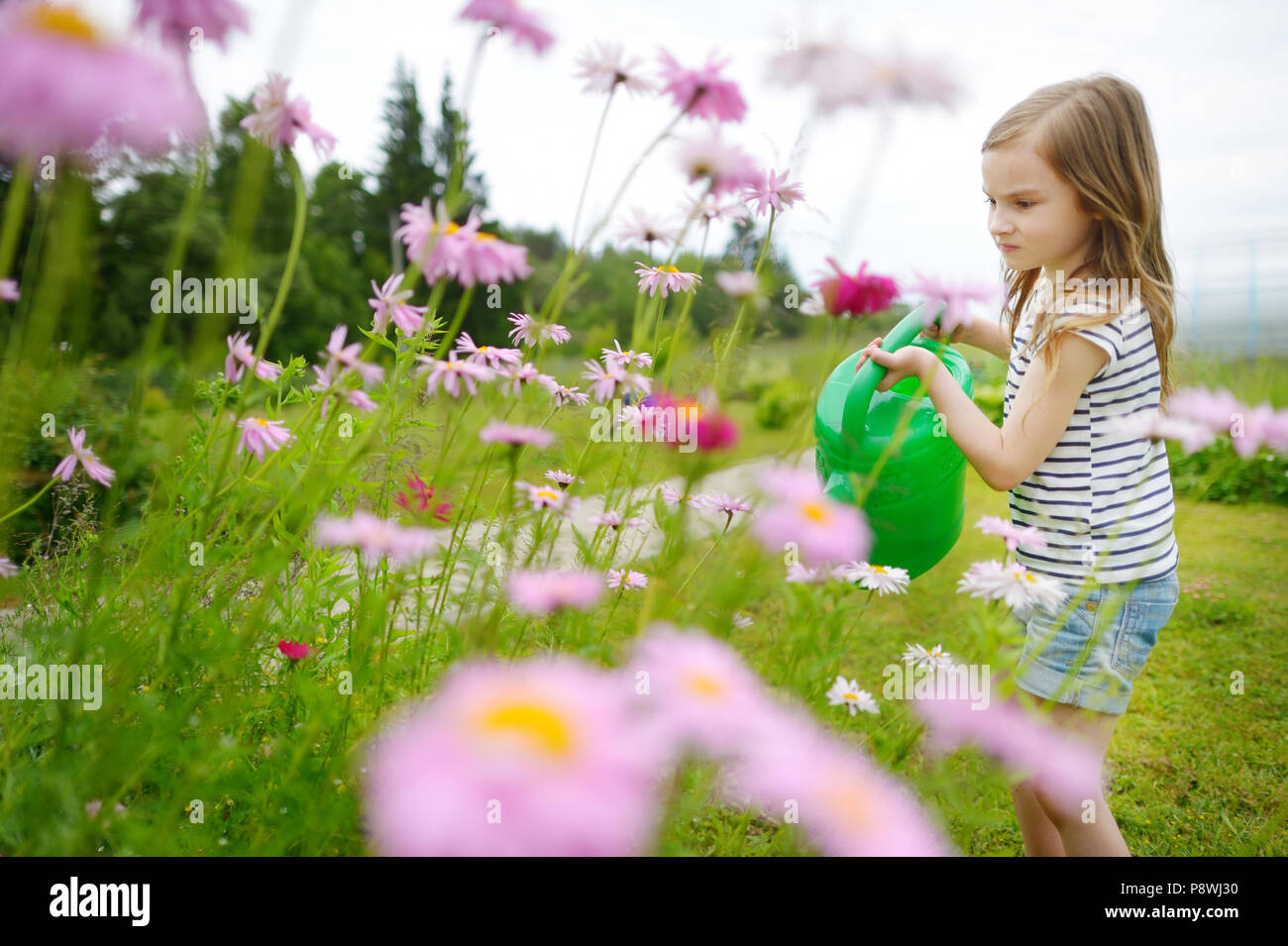 Adorable kleine Vorschüler Mädchen Bewässerung Blumen und Pflanzen im Garten Stockfoto