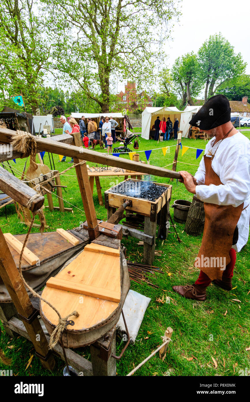 Living History, Re-enactment Veranstaltung. Der mittelalterliche Mensch, Schmied, mit Faltenbalg und Schmiede Eisen Waffen zu machen. Stockfoto