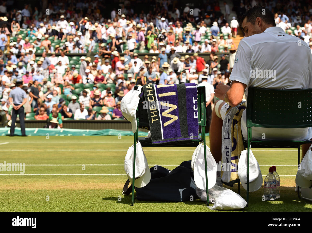 John Isner hat mehrere Caps hängen auf seinem Stuhl im Halbfinale der Männer  am Tag elf der Wimbledon Championships in der All England Lawn Tennis und  Croquet Club, Wimbledon Stockfotografie - Alamy