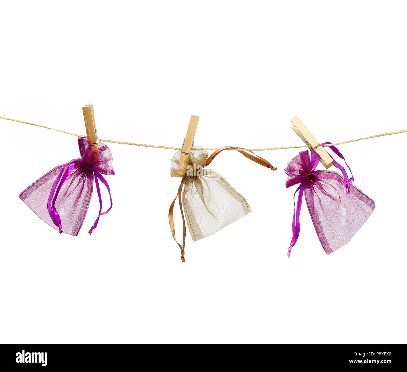 Drei farbigen kleines Geschenk Taschen hängen an einem Seil mit Wäscheklammern auf weißem Hintergrund. Stockfoto