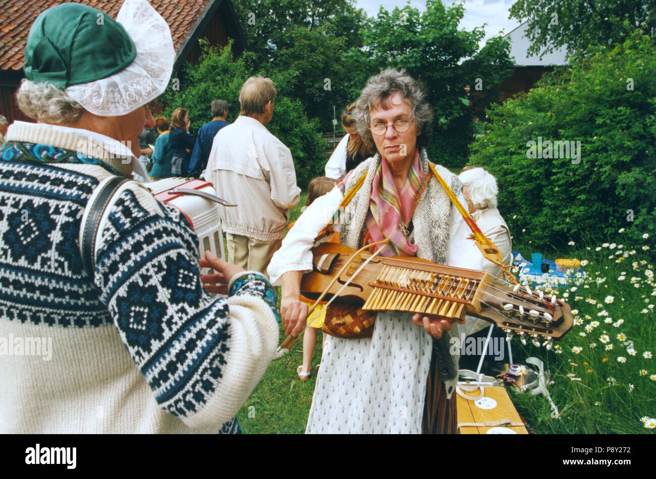Volksmusik im Hochsommer Frau in Folk Anzug spielt keyed Fiddle 2000 Stockfoto
