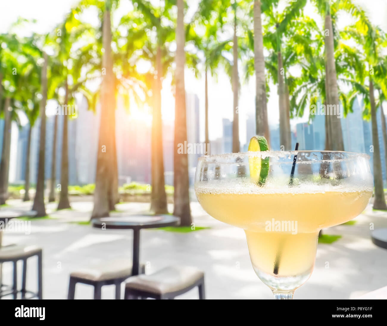 Trinken Margarita Cocktail in Singapur im Freien Cafe. Sonnenuntergang Stadtbild mit Palmen und Wolkenkratzer. Luxus Urlaub in modernen asiatischen Cit Stockfoto