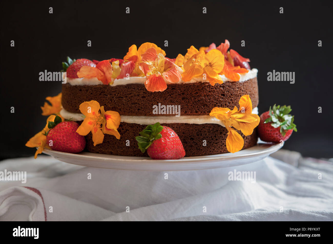 Essbare Blüten auf zweischichtigen Spice Kuchen mit Buttercream Vereisung Stockfoto