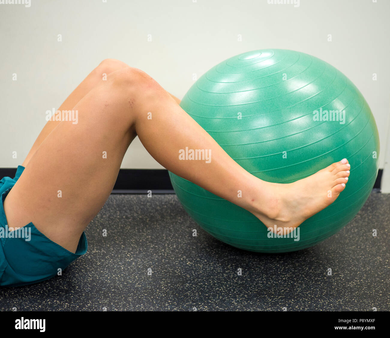 Athleten liegend mit den Beinen um einen Fitness Ball aus arbeiten und Übungen Stockfoto