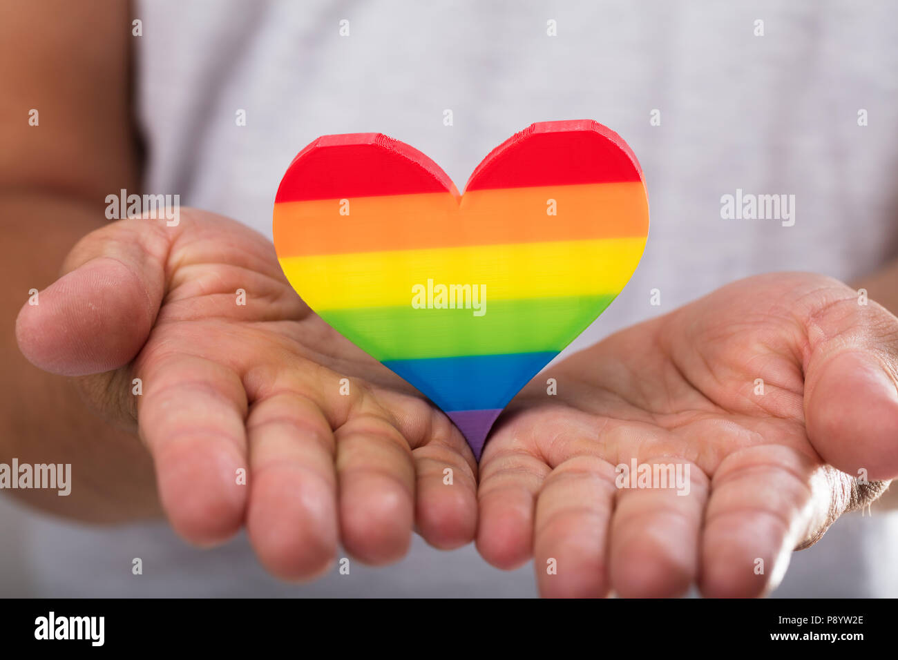 Nahaufnahme einer Hand, die Rainbow LGBT das Herz des Menschen Stockfoto