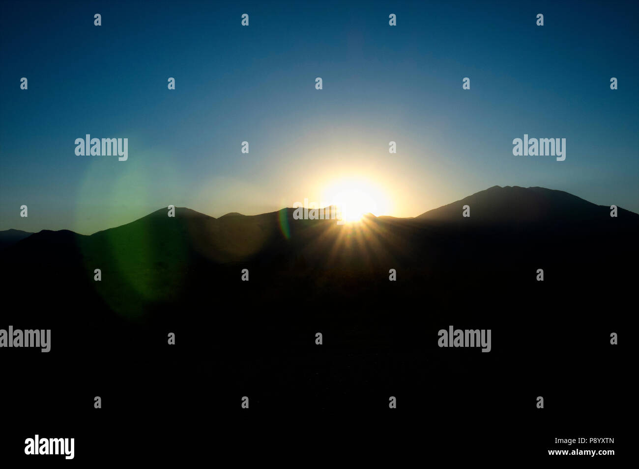 Lens Flare zusammen mit den Sonnenaufgang über Taos Mountain in der Sangre de Cristo Bergkette in Taos New Mexico Stockfoto
