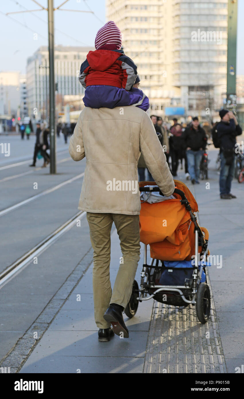 Berlin, Deutschland, Mensch sein Kind auf den Schultern und schiebt einen Kinderwagen Stockfoto