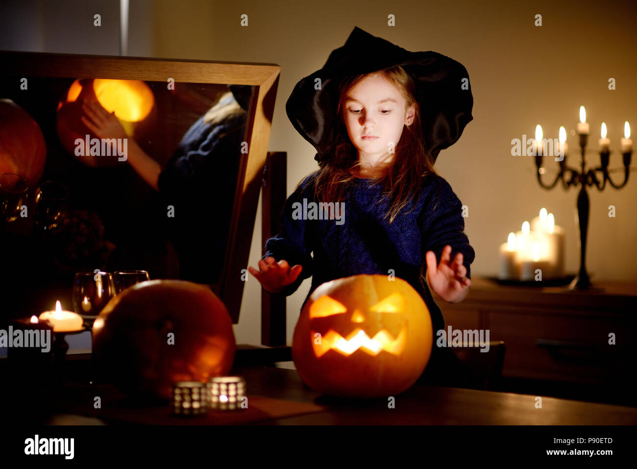 Adorable kleine Mädchen mit Halloween kostüm Spaß mit geschnitzten Kürbis im dunklen Zimmer an Halloween Stockfoto