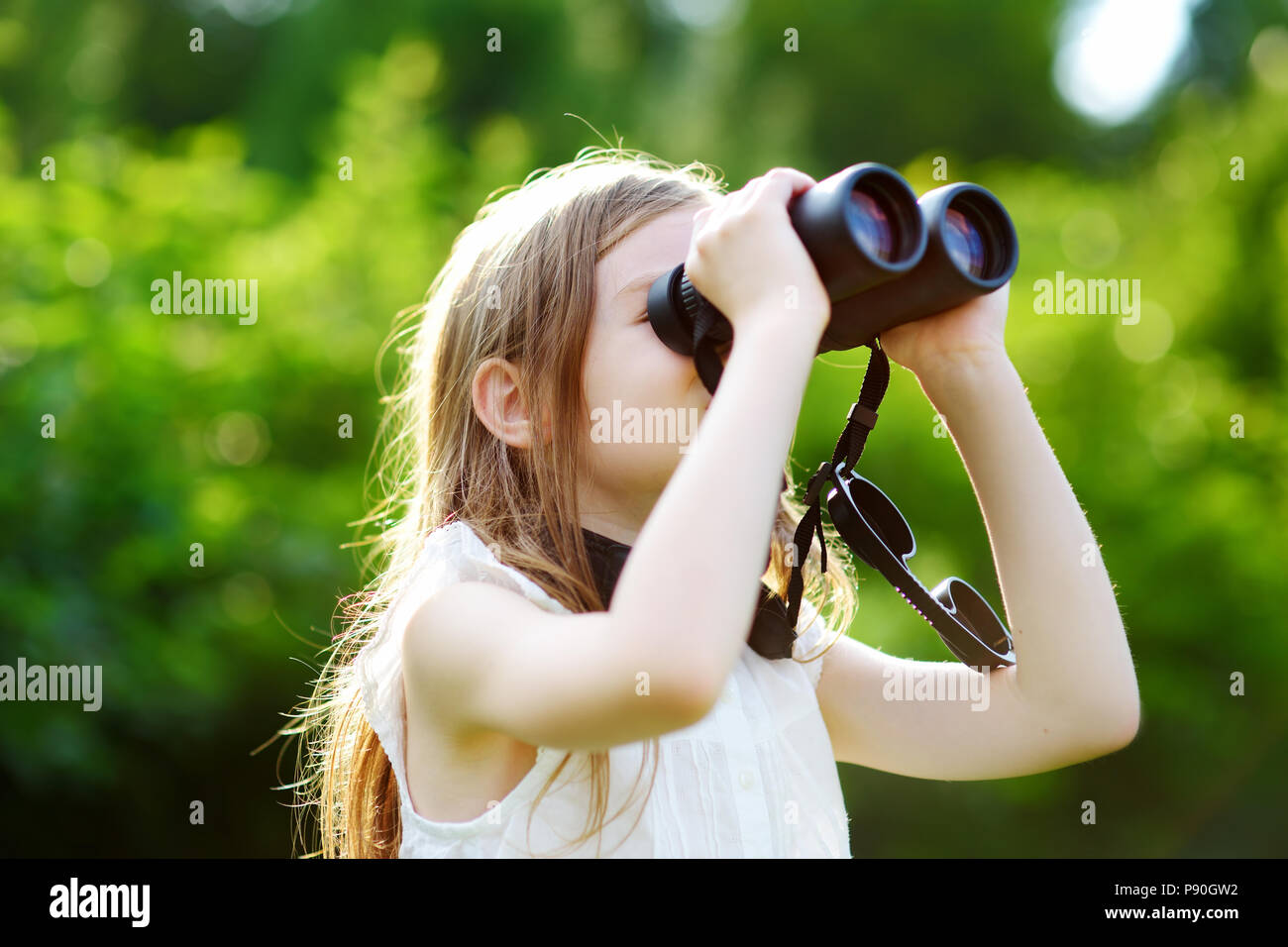 Lustige kleine Mädchen durch ein Fernglas an sonnigen Sommertagen suchen Stockfoto