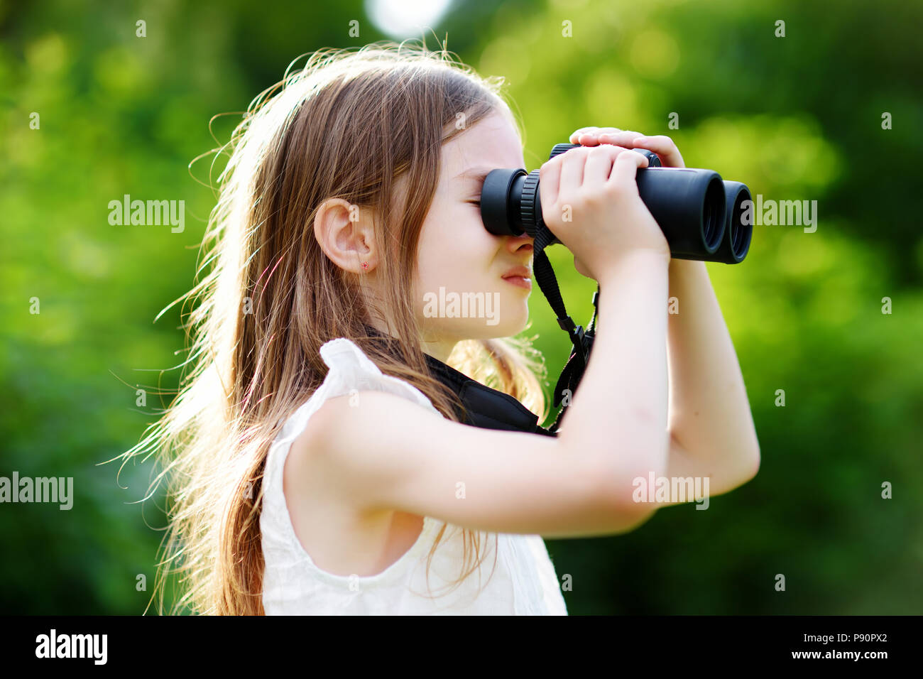 Lustige kleine Mädchen durch ein Fernglas an sonnigen Sommertagen suchen Stockfoto