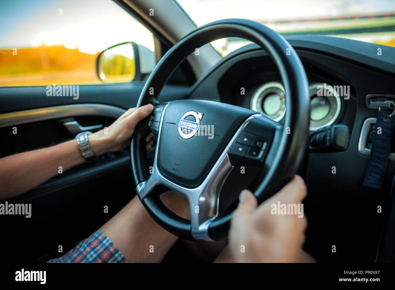 BERLIN/Deutschland - VOM 29. APRIL 2018: Fahrer in Shorts hält einen Volvo Lenkrad während der Fahrt mit dem Auto auf der Autobahn. Stockfoto