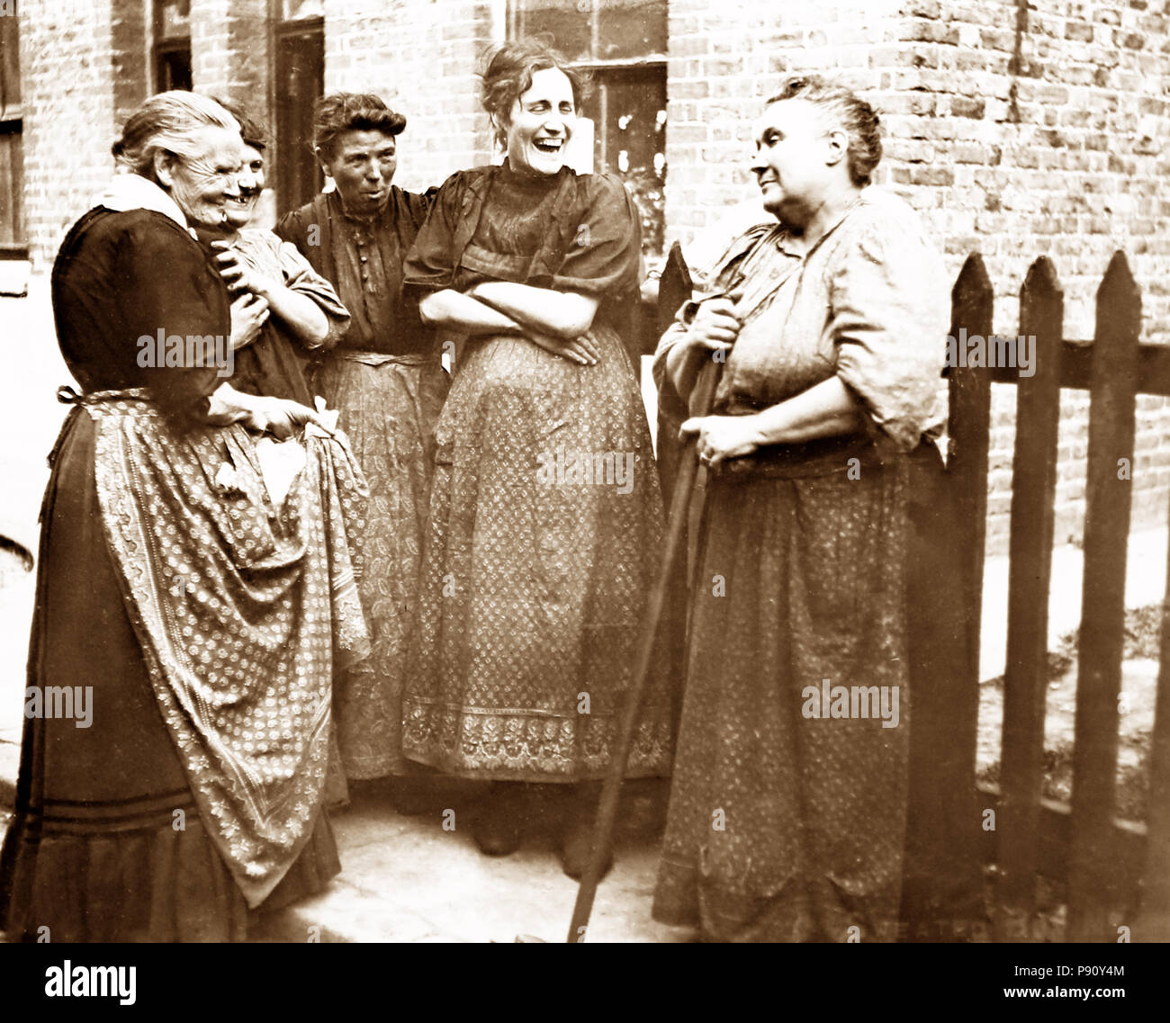 Meine Damen chatten durch den Zaun, Anfang 1900 s Stockfoto