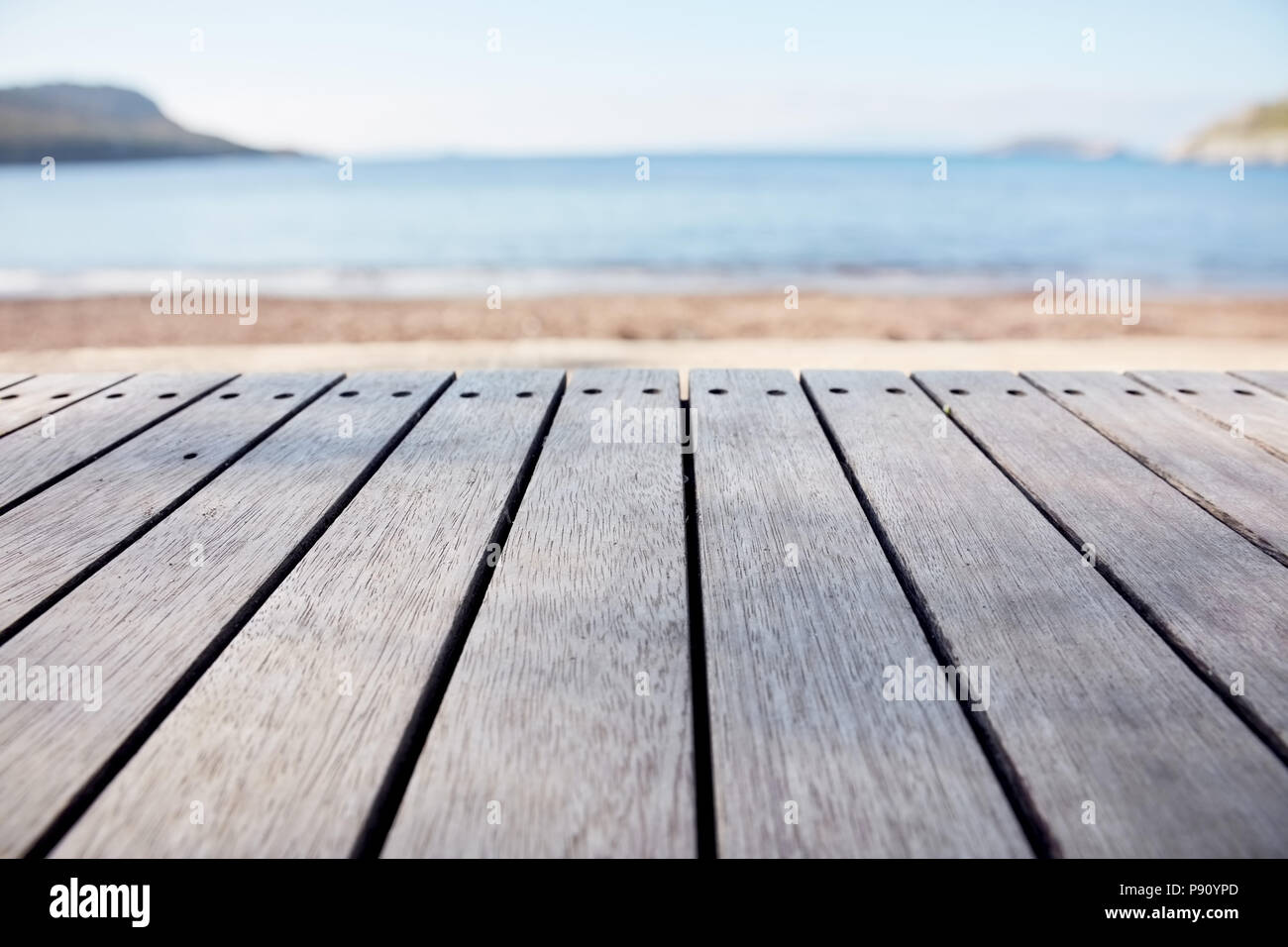 Leere Holzdeck Tabelle auf blurry Meer und Strand Hintergrund. Kopieren Sie Raum für Produkt anzeigen und zusammengesetzte Bilder. Stockfoto