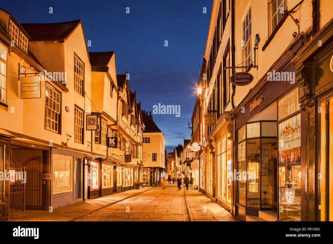 Twilight im Stonegate, York, North Yorkshire, England, UK. Käufer etwas Bewegung durch lange Belichtung verwischt. Stockfoto