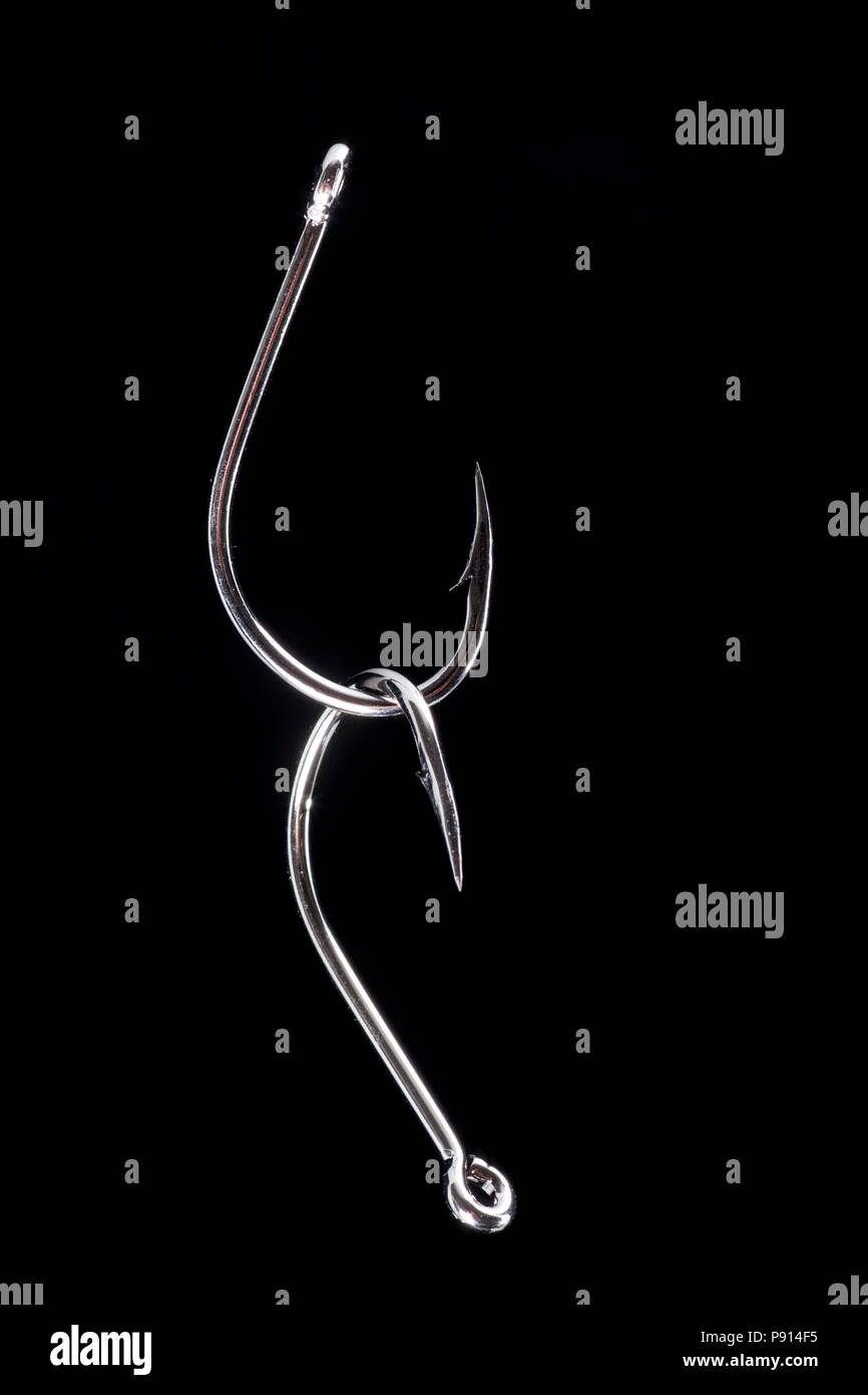 Ein Paar große, mit Widerhaken versehenen Angelhaken auf schwarzem Hintergrund fotografiert. Dorset England UK GB Stockfoto
