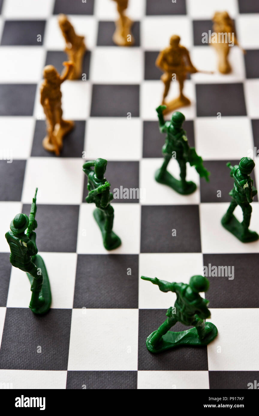 Zwei Armeen aus Kunststoff Spielzeug Soldaten einander gegenüber auf einem Schachbrett Stockfoto