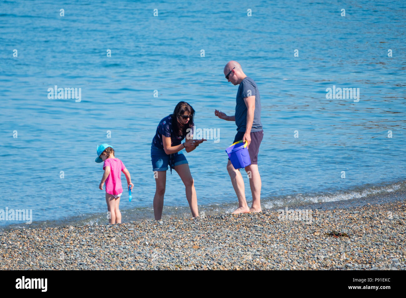 Aberystwyth Wales UK, Samstag, 14. Juli 2018 UK Wetter: Leute an den Strand und das Meer auf eine helle und sehr warmen und sonnigen Samstag Morgen in Aberystwyth an der Westküste von Wales. Die lange Zeit der heißen und ungewöhnlich trockene Wetter fort, wobei die Temperaturen wieder auf über 30 °C klettern in Teilen des Vereinigten Königreichs dieses Wochenende Foto: Keith Morris/Alamy leben Nachrichten Stockfoto