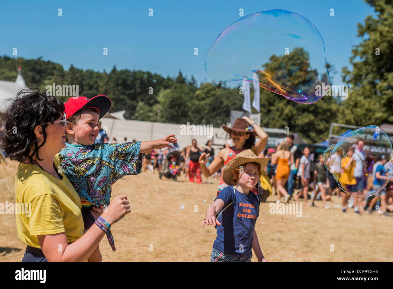 Suffolk, Großbritannien, 14. Juli 2018. Kinder und Erwachsene werden von der riesigen Blasen aus Bubble Inc - Die 2018 Latitude Festival, henham Park unterhalten. Suffolk vom 14. Juli 2018 Credit: Guy Bell/Alamy leben Nachrichten Stockfoto