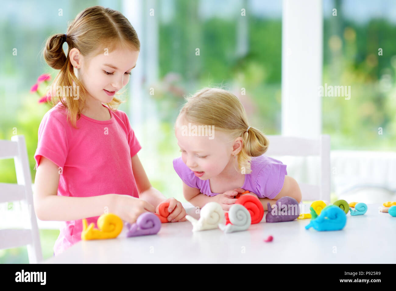 Zwei süße kleine Schwestern Spaß zusammen mit bunte Knetmasse in eine Kindertagesstätte. Kreative Kinder Formen zu Hause. Kinder spielen mit Plastilin oder Stockfoto