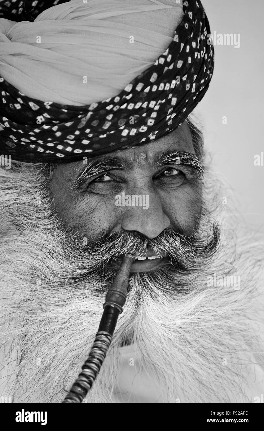 Ein Turbaned Rajasthani Mann demonstriert die Verwendung einer Shisha Leitung in das MEHERANGARH FORT - JOHDPUR, Rajasthan, Indien Stockfoto