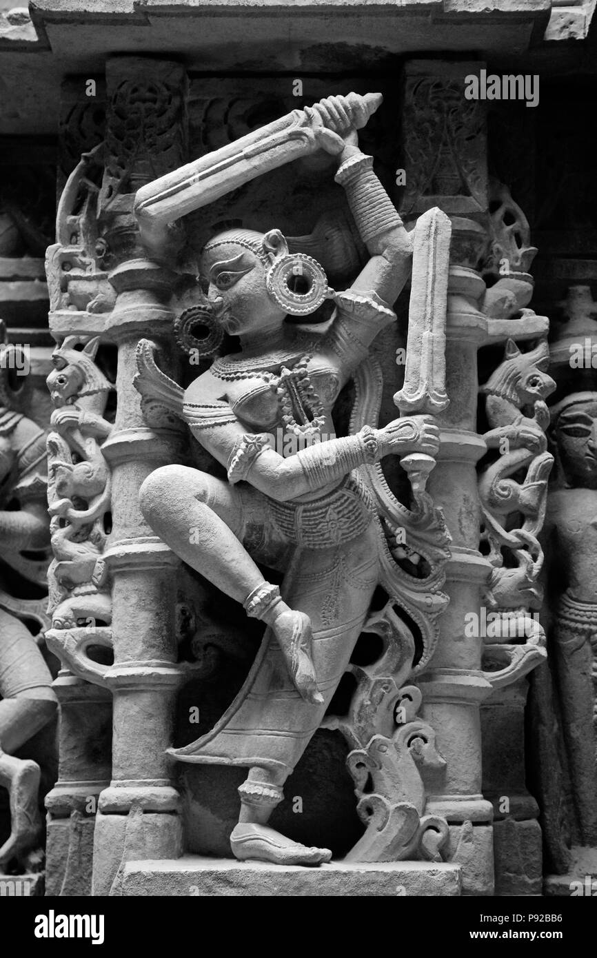 HAND GESCHNITZTEN SANDSTEIN DIVA mit Schwertern in einem alten Jain Tempel in Jaisalmer Fort - Rajasthan, Indien Stockfoto